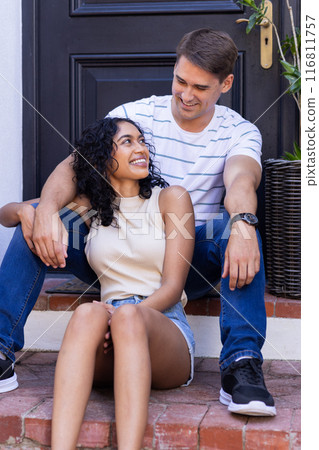 Smiling young couple sitting on steps, enjoying time together outdoors 116811757