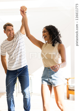 Dancing together, young couple enjoying time indoors, smiling and holding hands Dancing together, young couple enjoying time indoors, smiling and holding hands 116811773