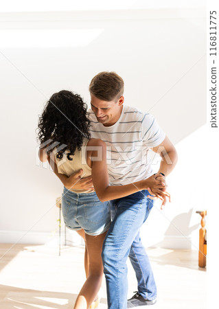 Young couple dancing together, enjoying fun and intimate moment indoors 116811775