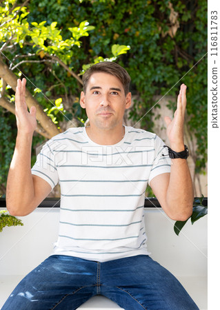 Man in casual wear on video call outdoors, raising hands in questioning gesture Man in casual wear on video call outdoors, raising hands in questioning gesture 116811783