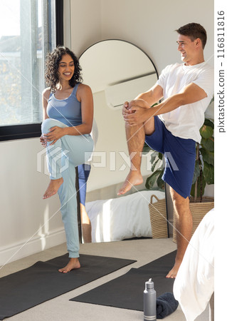 Practicing yoga together, young couple stretching on yoga mats in bedroom 116811816