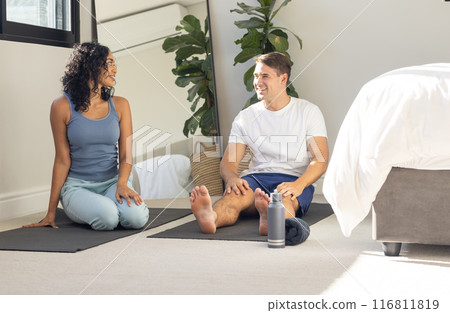 Practicing yoga, young couple sitting on mats and smiling at each other 116811819