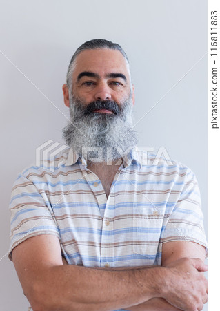 Smiling bearded senior man with crossed arms wearing striped shirt, looking confident 116811883