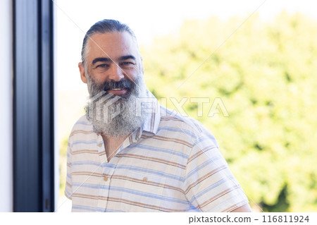 Smiling senior man with gray beard standing outdoors in casual striped shirt Smiling senior man with gray beard standing outdoors in casual striped shirt 116811924