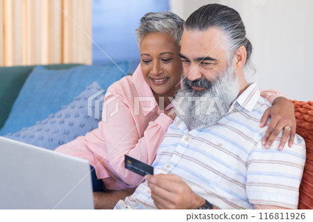 Senior couple online shopping with credit card and laptop, sitting on couch Senior couple online shopping with credit card and laptop, sitting on couch 116811926