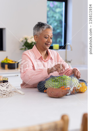 Unpacking groceries, senior woman organizing fresh vegetables in kitchen counter 116811934