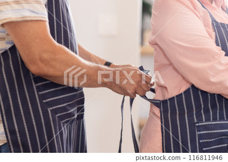 Tying apron, senior couple preparing to cook together in kitchen 116811946