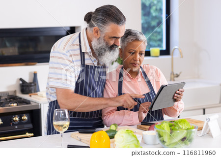 Cooking together, senior couple using tablet for recipe in modern kitchen Cooking together, senior couple using tablet for recipe in modern kitchen 116811960