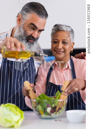 Senior couple preparing salad together, pouring olive oil and mixing ingredients Senior couple preparing salad together, pouring olive oil and mixing ingredients 116811968