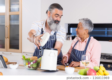 Cooking together, senior couple preparing meal with rice cooker and fresh vegetables Cooking together, senior couple preparing meal with rice cooker and fresh vegetables 116811969