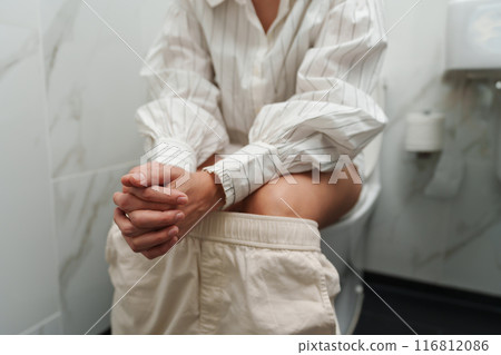 close up woman sitting on a toilet bowl in bathroom close up woman sitting on a toilet bowl in bathroom 116812086