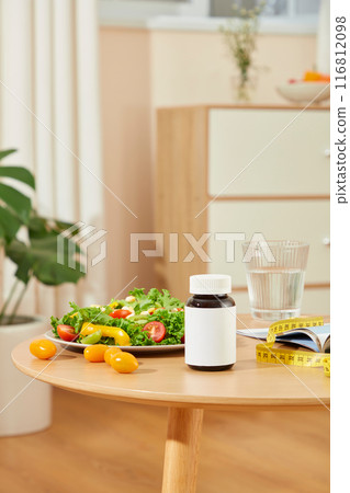 The unique template to design advertising pic of weight losing supplement, on the top of wooden table displaying some losing weight items and an unbranded drug bottle in center 116812098