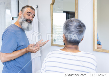 Senior couple talking and looking at each other in bathroom mirror 116812323