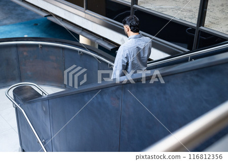 Walking down modern office staircase, man in business attire heading to work, copy space Walking down modern office staircase, man in business attire heading to work, copy space 116812356