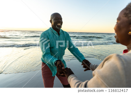 Senior African American couple enjoys a playful moment on the beach, with copy space Senior African American couple enjoys a playful moment on the beach, with copy space 116812417