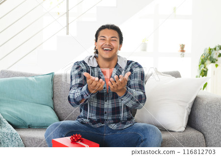 Young biracial man laughing joyfully during a video call in a home setting Young biracial man laughing joyfully during a video call in a home setting 116812703