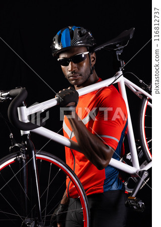African American man poses with his bicycle on a black background, with copy space 116812737