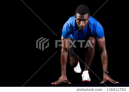 African American man in starting position for a sprint, with copy space on a black background 116812782