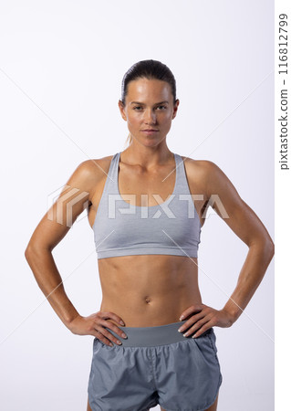 Young Caucasian female athlete stands confidently in sportswear on a white background Young Caucasian female athlete stands confidently in sportswear on a white background 116812799
