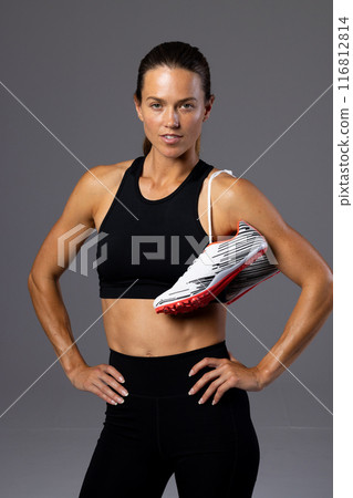 Young Caucasian female athlete poses confidently in fitness attire on a white background Young Caucasian female athlete poses confidently in fitness attire on a white background 116812814
