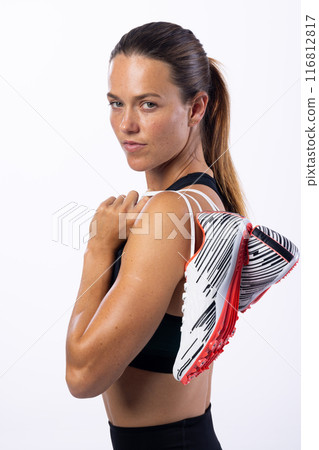Young Caucasian female athlete holds running shoes over her shoulder on a white background 116812817