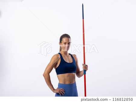 Confident young Caucasian female athlete with javelin poses on white, space for text Confident young Caucasian female athlete with javelin poses on white, space for text 116812850