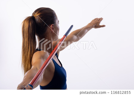 Young Caucasian female athlete practices javelin throwing technique indoors on a white background 116812855