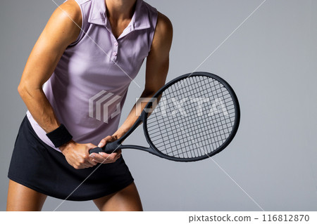 Athlete in tennis attire poses with a racket on a white background, with copy space 116812870