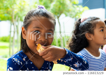 Biracial girl in blue, eating lunch, smiles at the camera at school Biracial girl in blue, eating lunch, smiles at the camera at school 116813229