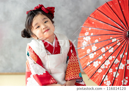 A girl wearing a kimono sitting upright A girl wearing a kimono sitting upright 116814120