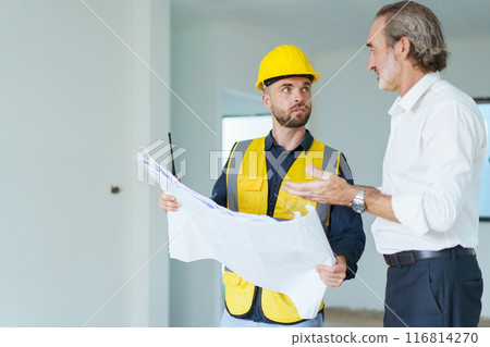 Portrait of caucasian male real estate customer talking - discussing with male building foreman - engineer about construction and interior works. Construction contractor talking with client. Portrait of caucasian male real estate customer talking - discussing with male building foreman - engineer about construction and interior works. Construction contractor talking with client. 116814270