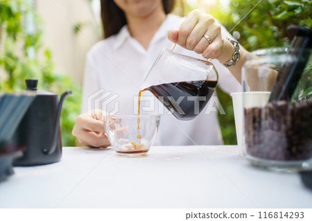 Happy Asian beautiful woman making a specialty coffee in morning at her backyard garden, woman brewing a coffee by dripping or pouring over a hot water. 116814293