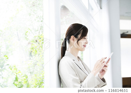 Profile of a young woman operating a smartphone 116814631