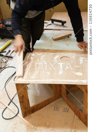 A worker applies glue to veneer 116814730
