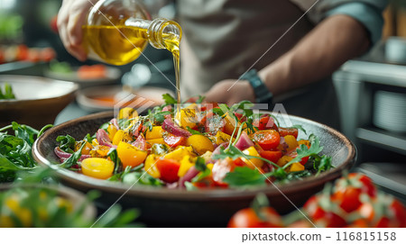 A chef's hands drizzle olive oil over salad of cherry tomatoes and fresh greens A chef's hands drizzle olive oil over salad of cherry tomatoes and fresh greens 116815158