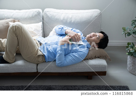 Man lying down on sofa 116815868