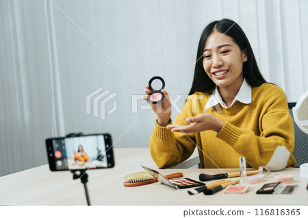 Young Asian beauty blogger is showcasing cosmetic products as well as tutorials on how to apply and record makeup tutorials on social media networks. Young Asian beauty blogger is showcasing cosmetic products as well as tutorials on how to apply and record makeup tutorials on social media networks. 116816365