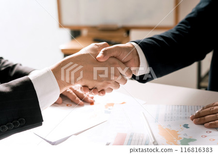 Entrepreneurs collaboration deal shaking hands in a modern office and financial paper graph on desk. Entrepreneurs collaboration deal shaking hands in a modern office and financial paper graph on desk. 116816383