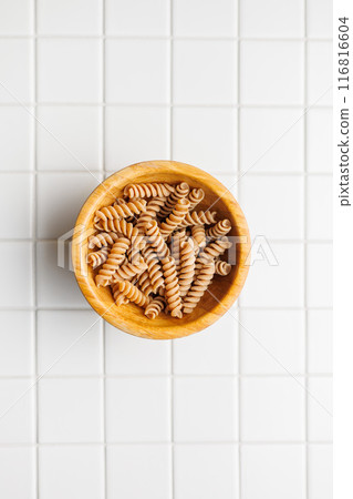 Uncooked whole grain pasta. Raw fusilli in bowl. Top view. Uncooked whole grain pasta. Raw fusilli in bowl. Top view. 116816604