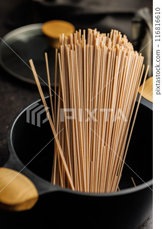 Uncooked whole grain pasta. Raw spaghetti in black pot. Uncooked whole grain pasta. Raw spaghetti in black pot. 116816610
