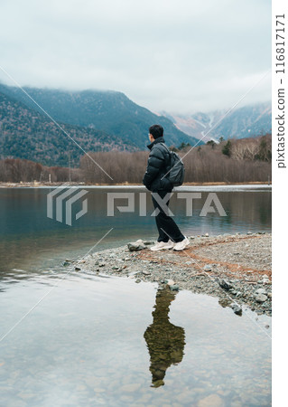 man  tourist travel Kamikochi National Park, happy Traveler sightseeing Taisho pond with mountain, Nagano Prefecture, Japan. Landmark for tourists attraction. Japan Travel, Destination and Vacation 116817171