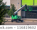 Calgary, Alberta, Canada. Jul 20, 2024. A green telescopic boom lift is positioned in front of a commercial building, with its platform elevated for maintenance work. 116819602