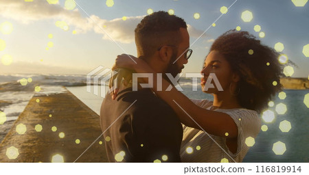 Image of spots of light over happy diverse couple embracing by sea 116819914