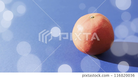 Composition of orange and spots of light over blue background Composition of orange and spots of light over blue background 116820036