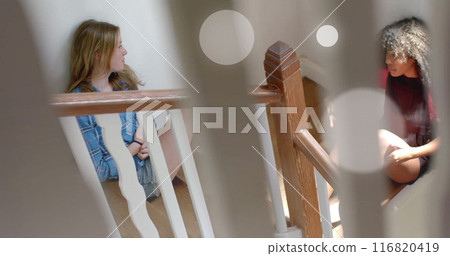 Image of light spots over two diverse teenage girls talking sitting on stairs at home Image of light spots over two diverse teenage girls talking sitting on stairs at home 116820419