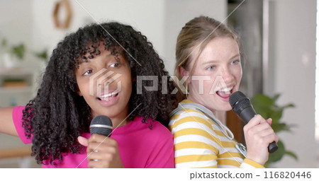 Image of white lights over happy diverse teenage girls with microphones singing karaoke at home Image of white lights over happy diverse teenage girls with microphones singing karaoke at home 116820446