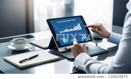 Financial analyst working at modern desk with tablet showing financial data 116820672