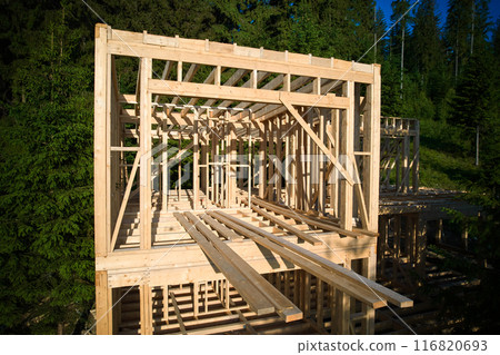 Drone's vantage point offers view of two-storey wooden-framed domicile in process of construction near forest. Idea of contemporary ecological construction and modern architectural design. 116820693