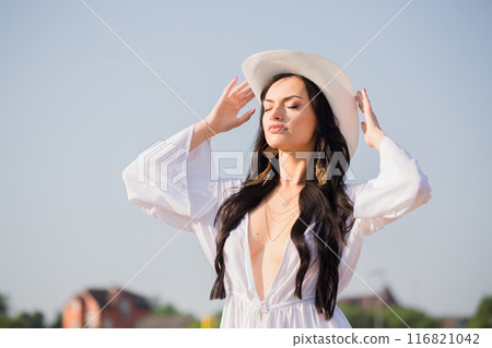 A woman in a white hat against a blue sky in summer 116821042
