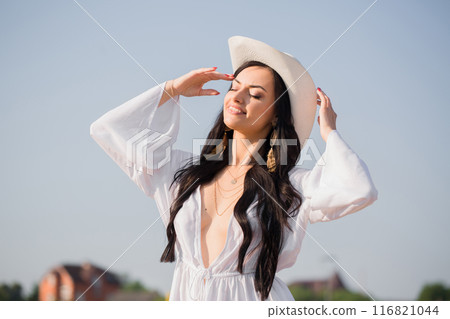 Portrait of a young woman with long hair in a hat on the beach in summer 116821044